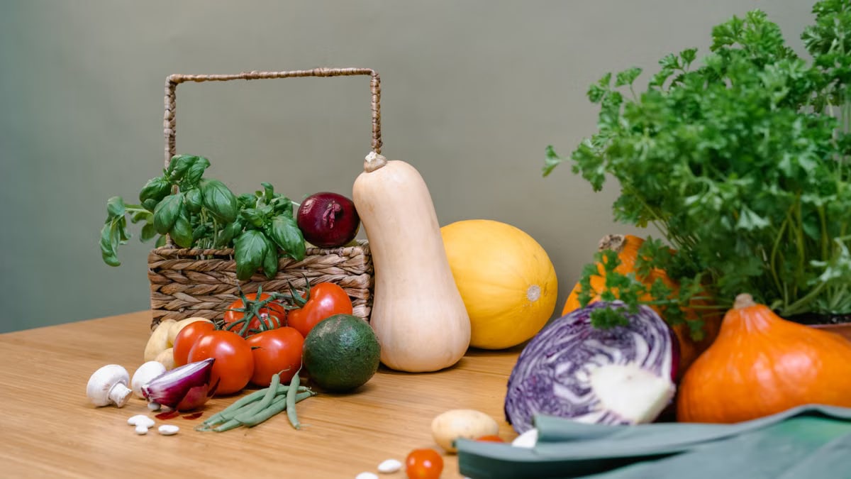 Assorted fresh vegetables and herbs on a wooden table enhancing culinary inspiration.
